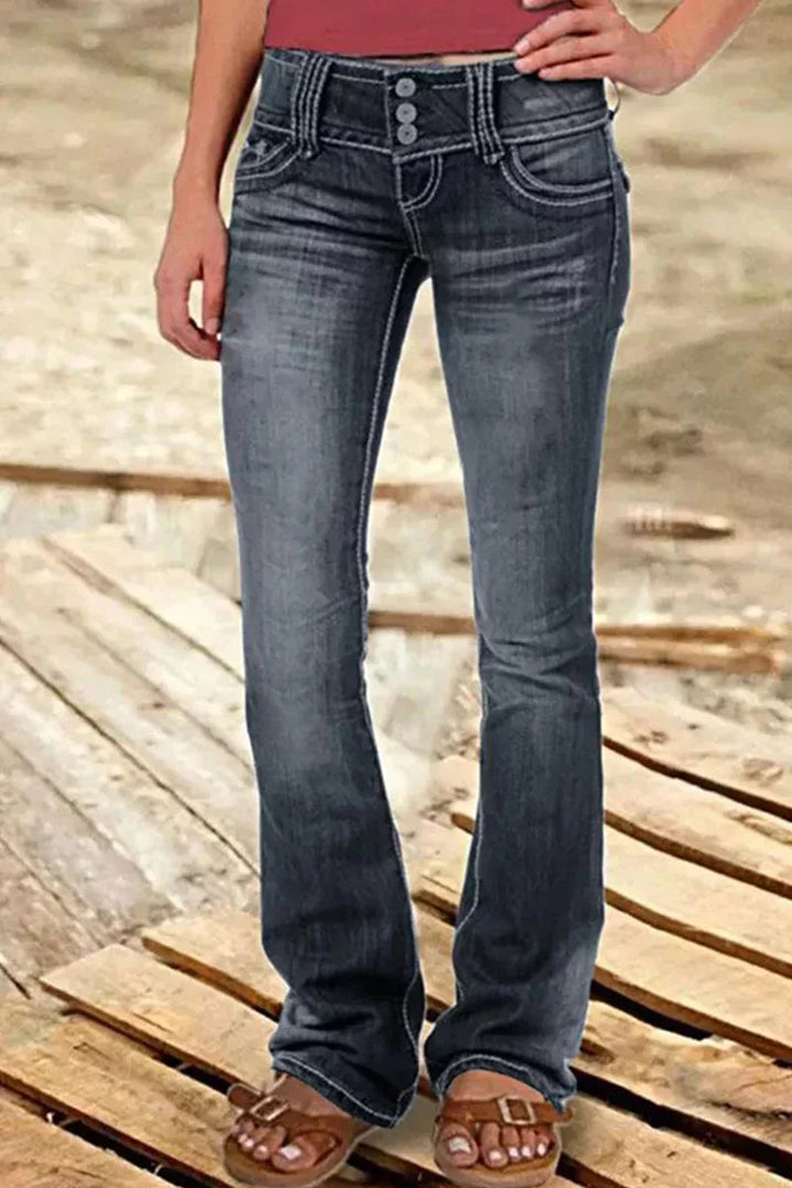 Närbild av den höga midjan och knappgylfen på kvinnors slitna bootcut jeans i denim