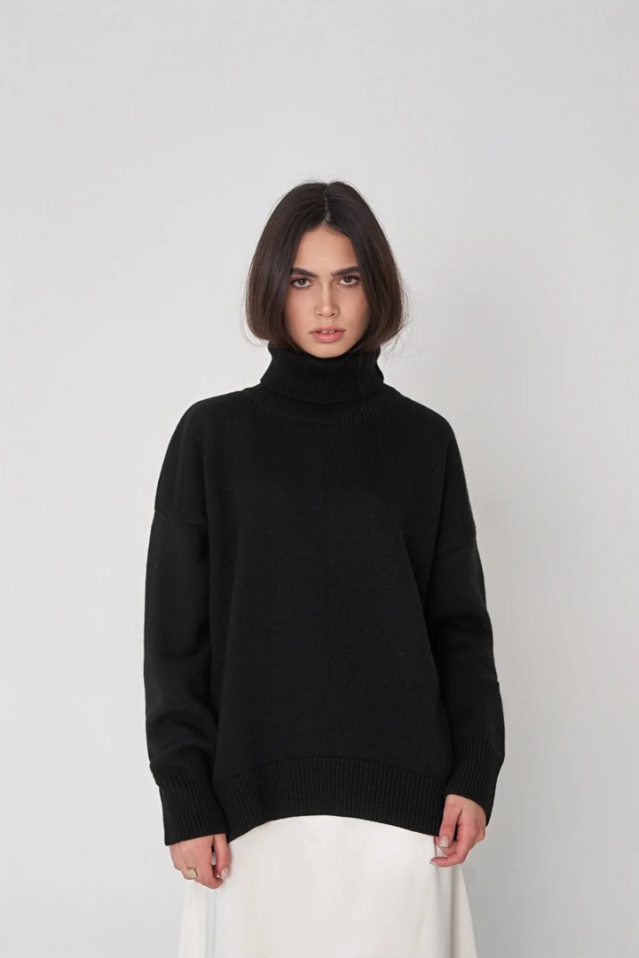 Kvinna bär lösstickad grön tröja med hög hals. Elegant och bekväm för dammode.