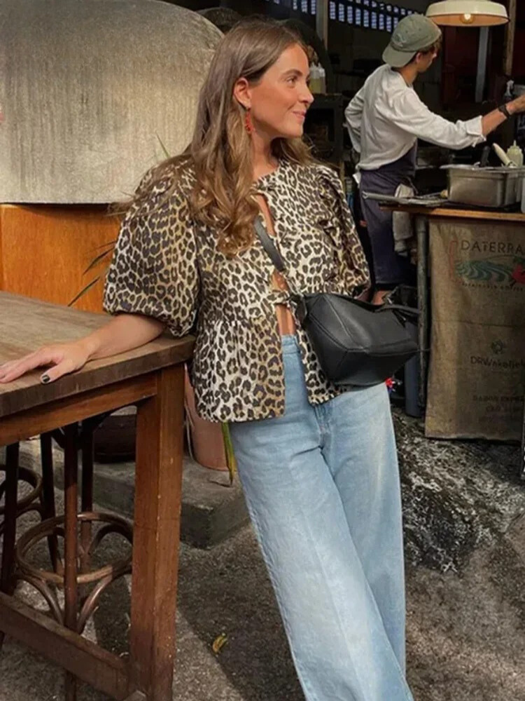 Elegant baksida av kvinnors leopardblus med puffärm och peplum. En trendig festtopp med djurmönster.