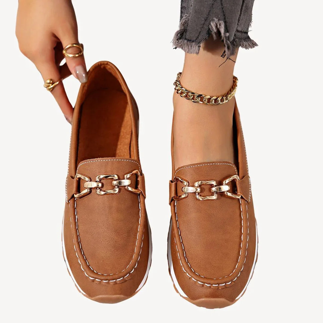 Klassiska slip-on loafers för dam med modern kedjedetalj. Elegant stil för arbete och vardag.