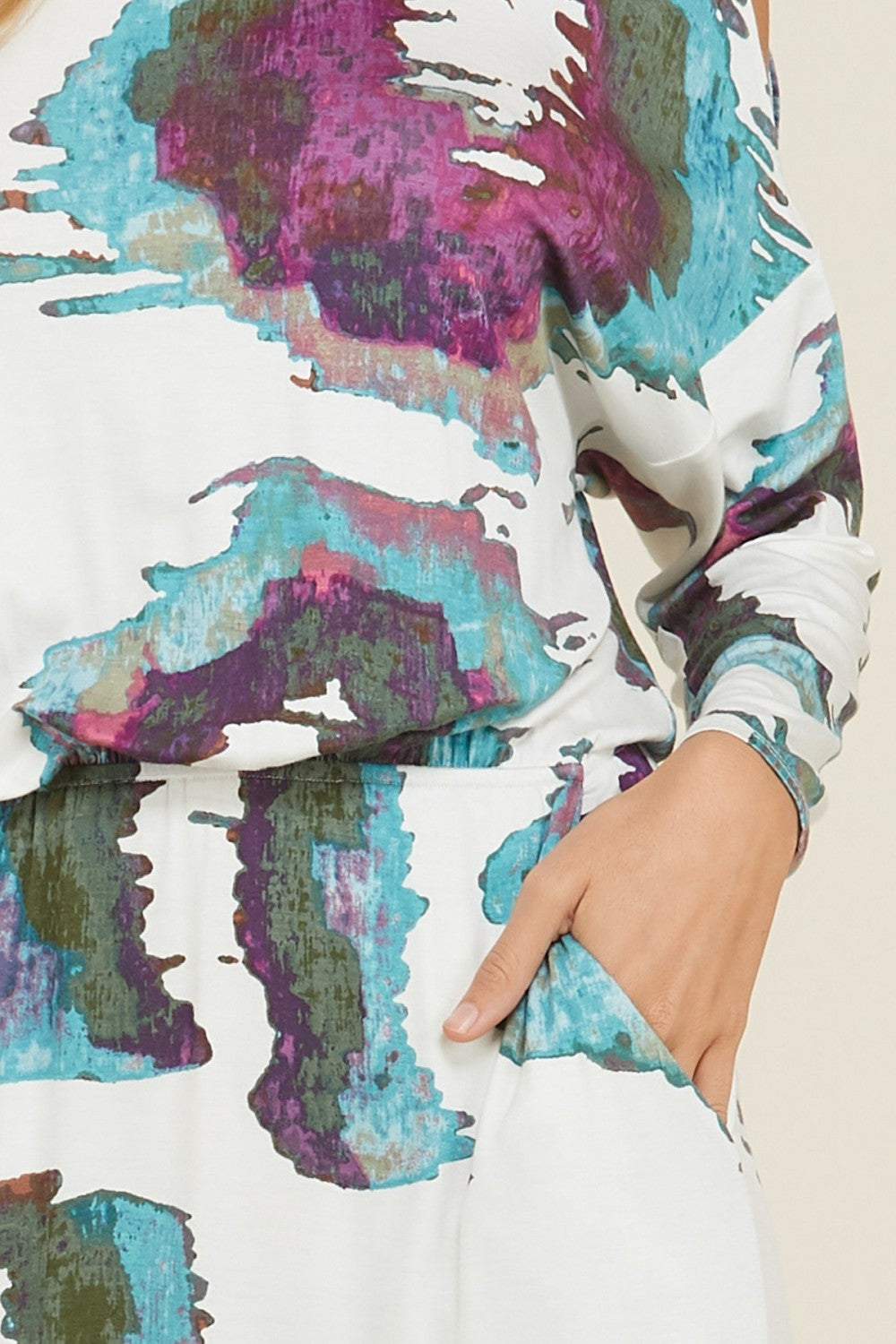 Lång kvinnors klänning med öppen axel, flödande design och praktiska fickor. Trendig casual sommarlook.