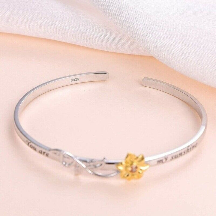 Närbild av solrosarmband för kvinnor, detaljerad blommig design. Glänsande smycke i kopparlegering, perfekt accessoar.