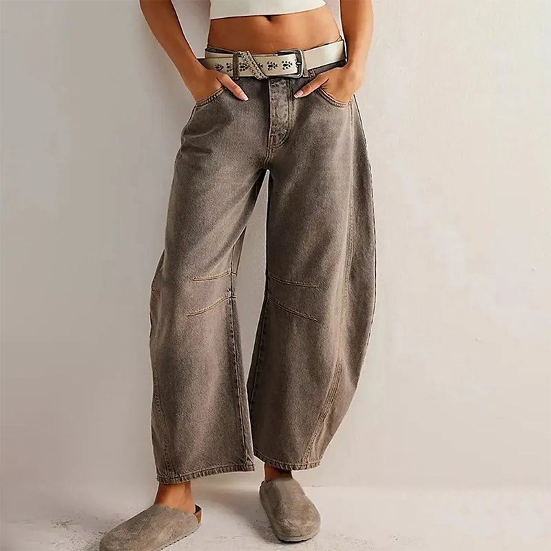 Detaljbild av beige utsvängda jeans med låg midja för kvinnor, visar tygets stretch och sömmar.