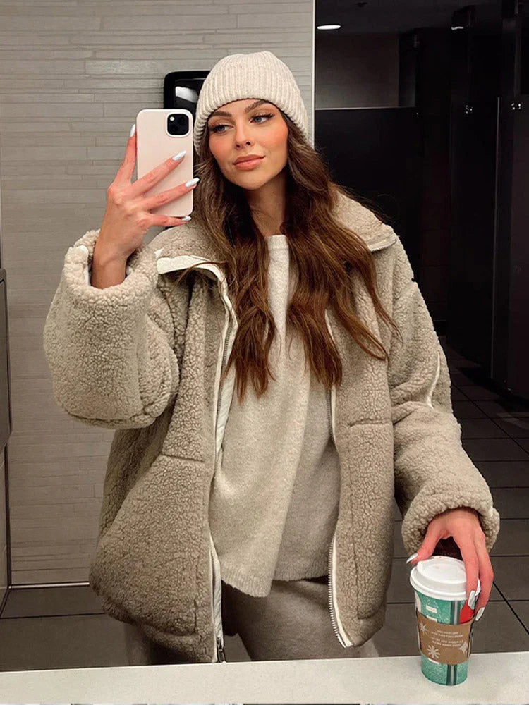 Elegant lång damjacka i teddy, mjuk och beige med trendig lös passform för en avslappnad look.