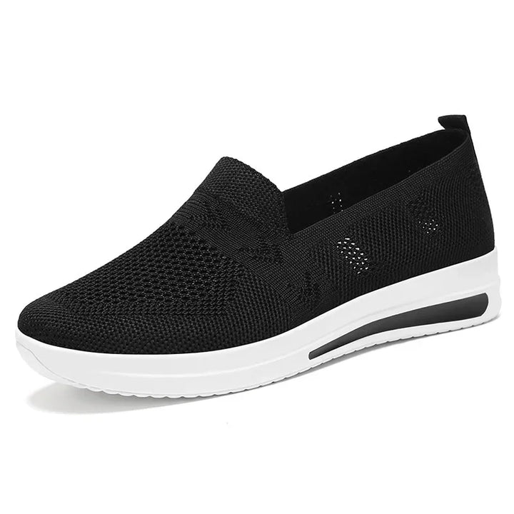 Ett par vita, andningsbara kvinnors sneakers. Mångsidiga och bekväma skor för vår och sommar.