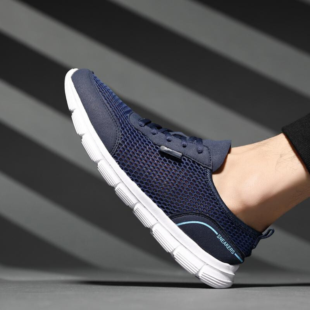 Detaljbild av andningsbart nät på gråa herr löparskor. Komfortabla sneakers för aktiv livsstil och sport.