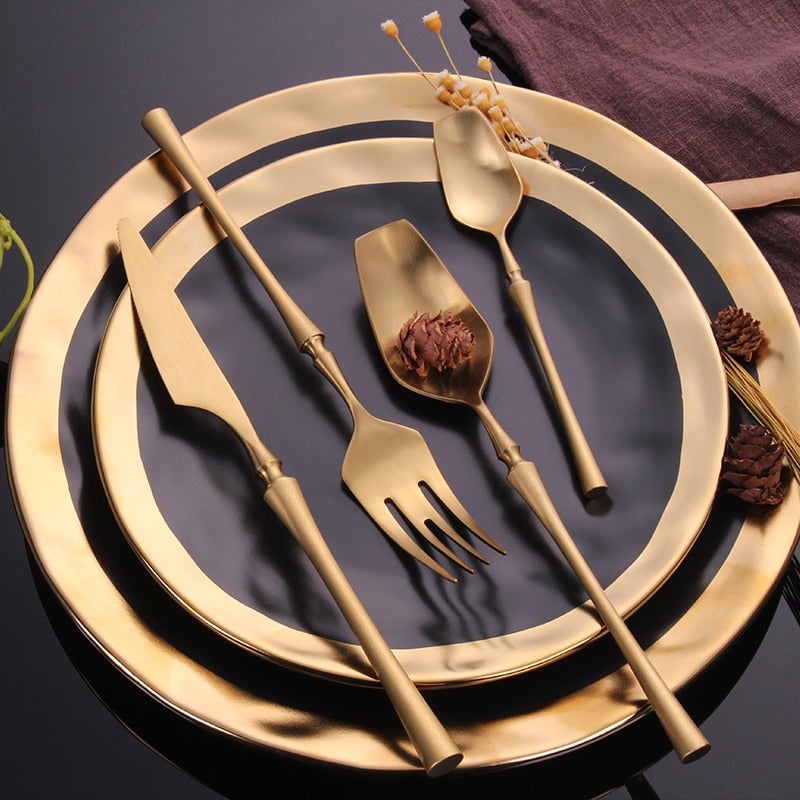 Detaljbild av elegant guldbestick kniv och gaffel, glänsande heminredning, middagsservis.