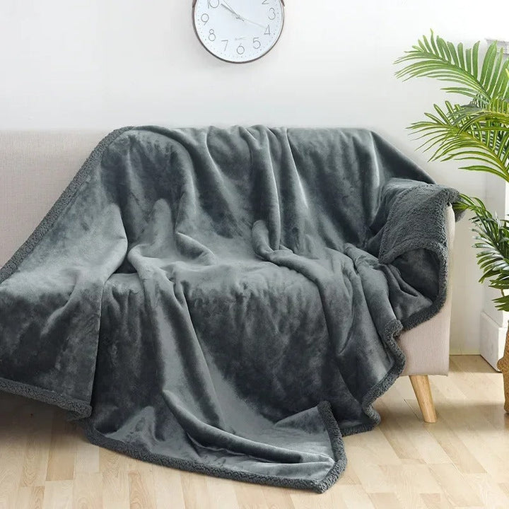 Stor, varm shaggy filt draperad över en soffa, skapar en inbjudande och mysig atmosfär i vardagsrummet.