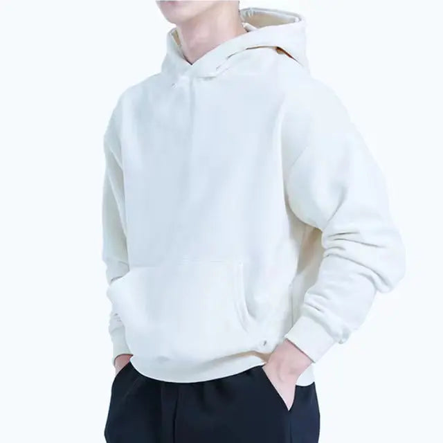 Man bär en grå herrhoodie med ledig passform, kombinerad med jeans för en avslappnad stil.