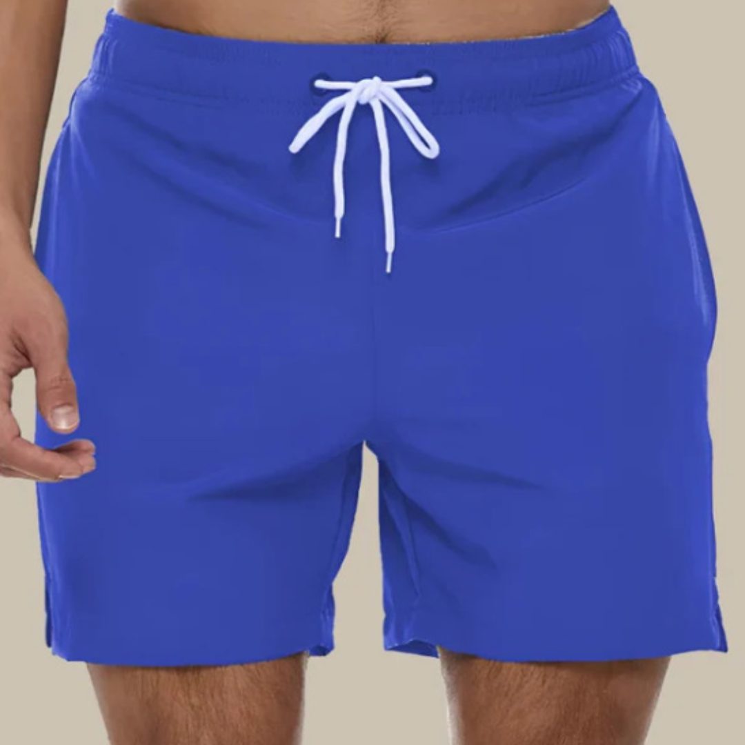 Man bär snabbtorkande badshorts på stranden, redo för simning och sol.
