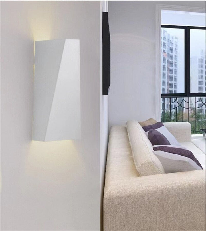 Minimalistisk LED-vägglampa i geometrisk form. Ger modern accentbelysning och stilren heminredning i järn.