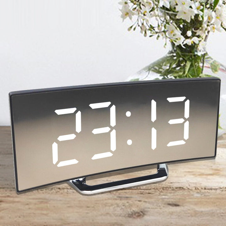 Vit LED-väckarklocka med minimalistisk design mot en ljus bakgrund, visar klar tids- och temp-info.