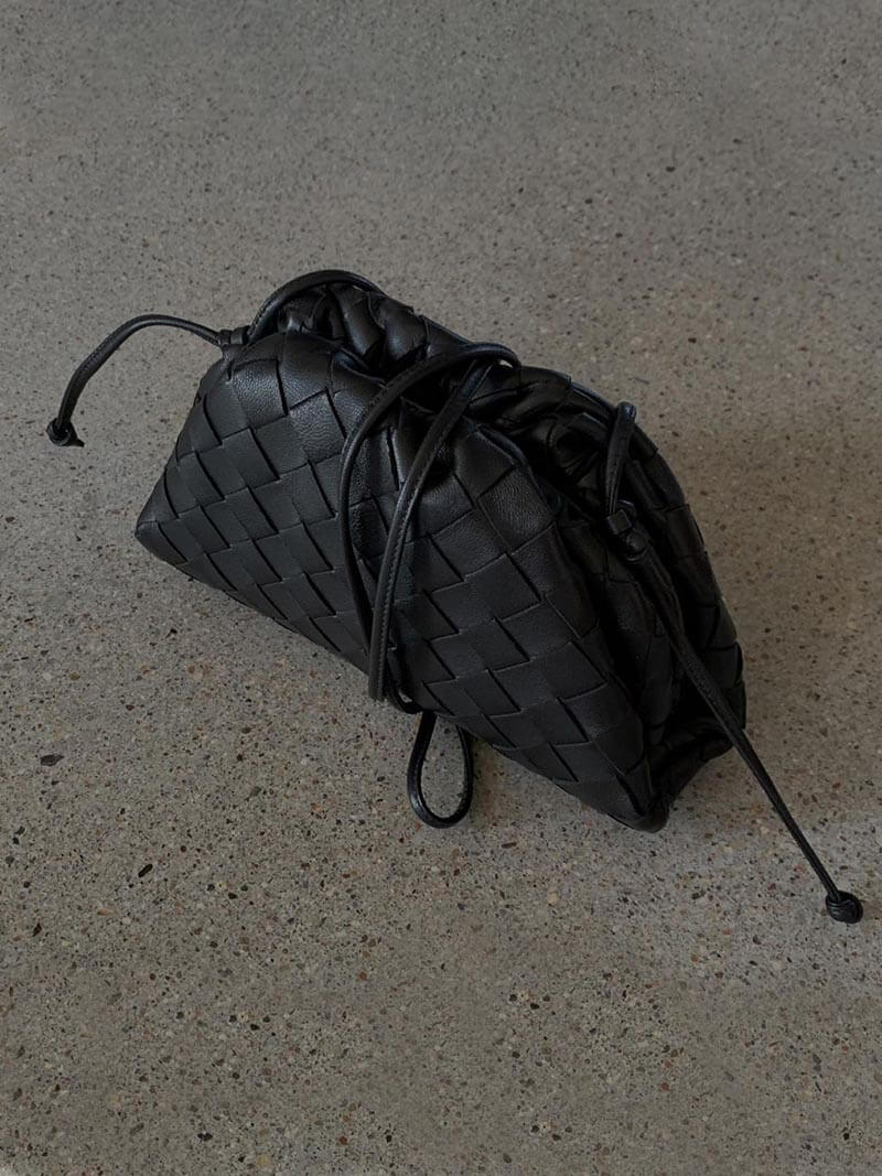 Miniväska i elegant svart vävd design med handtag, framifrån, damväska.