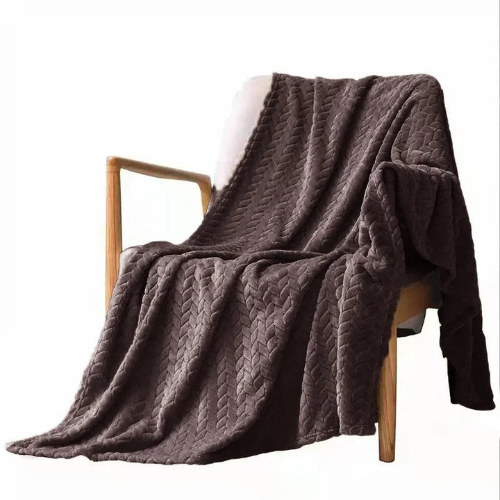 Snygg sammetsfilt i korall, draperad över en soffa för extra värme och stil i vardagsrummet.