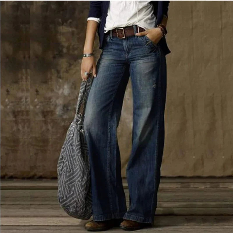 Närbild på tyget av grå vida vintage damjeans med hög midja, visar textur och söm.