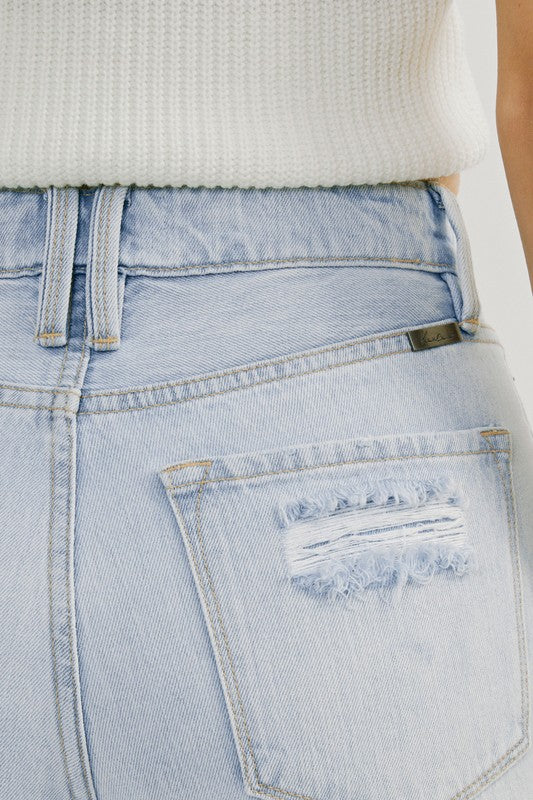 Detaljer av de trendiga högmidjade distressade ljus denim jeansen för kvinnor, visar färg och passform. Smickrande jeans.