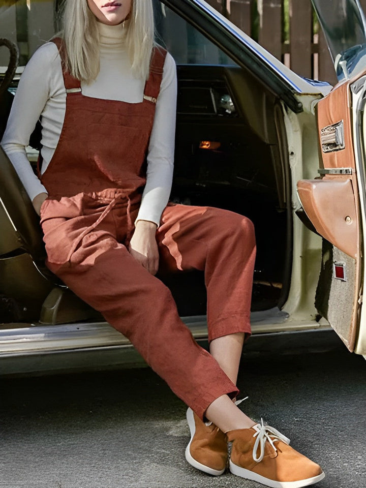 Avslappnad damjumpsuit i röd-orange färg, ärmlös design med justerbara band för sommaroutfit.