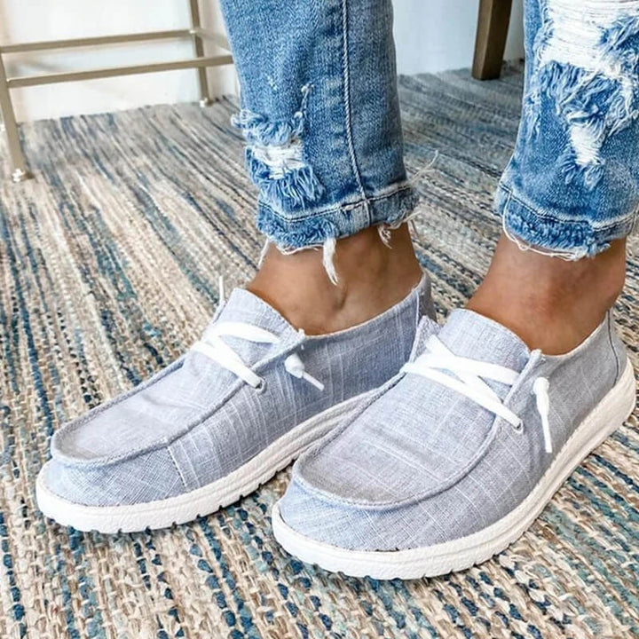 Närbild på snörningen och det rutiga mönstret på rosa canvas loafers för dam