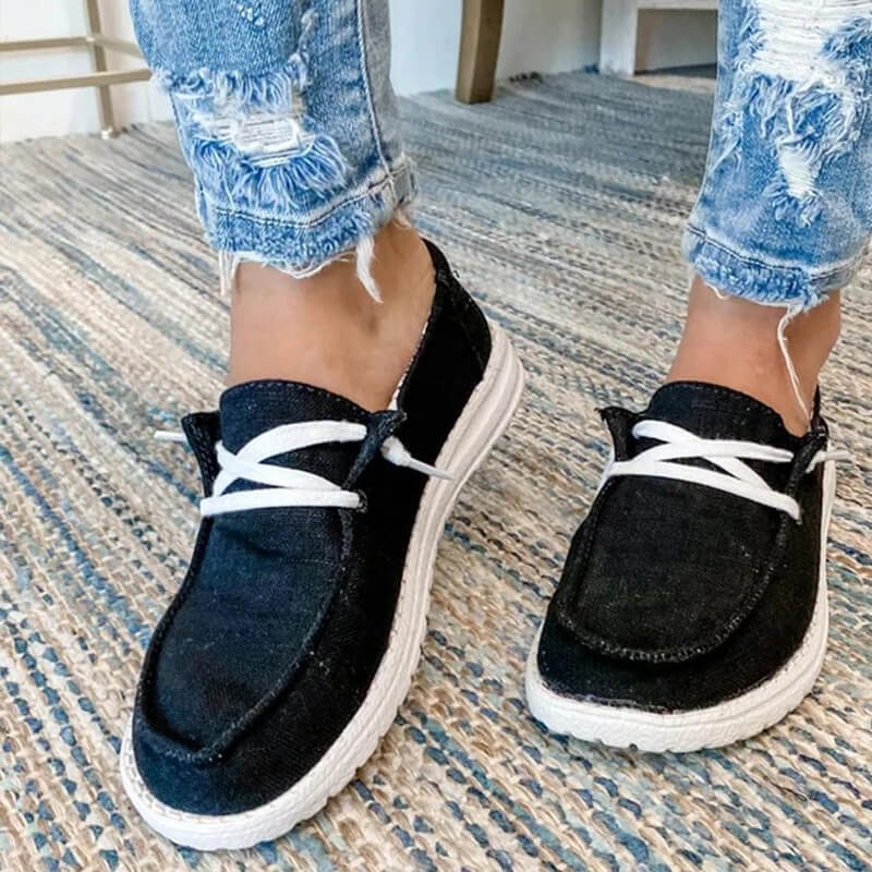 Detaljbild av canvasmaterialet och sömmarna på rosa damloafers med snörning