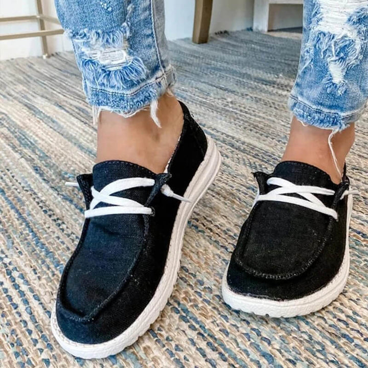 Detaljbild av canvasmaterialet och sömmarna på rosa damloafers med snörning
