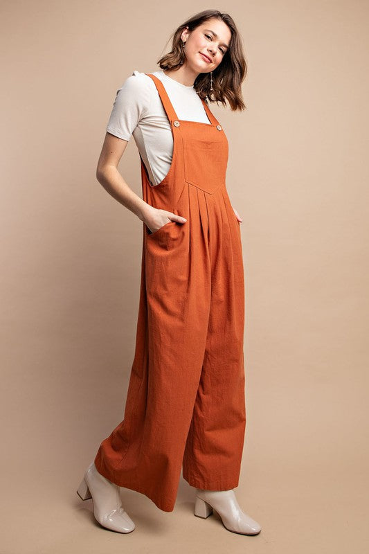 Kvinnlig byxdress i rostfärg med smarta fickor och sofistikerade pintuck-sömmar. Mångsidig vardagslook.