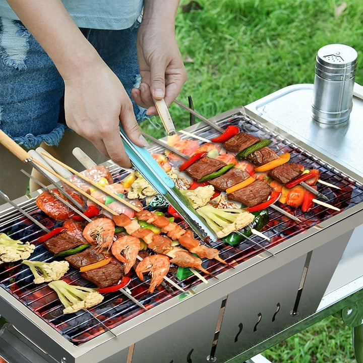 Kompakt kolgrill i rostfritt stål, perfekt för utomhusmatlagning, camping och resvänliga utflykter.