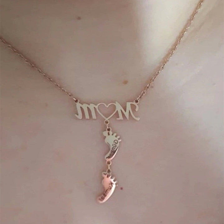 Detaljer av mammahalsband med babyfötter och gravyr av namn. Ett kärt minne i silver, guld eller roséguld.