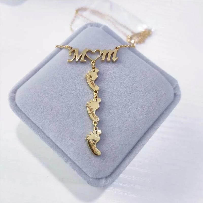 Kvinna bär stilrent mammahalsband med babyfötter i silver. Ett personligt och älskat familjesmycke.