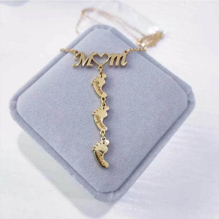 Kvinna bär stilrent mammahalsband med babyfötter i silver. Ett personligt och älskat familjesmycke.
