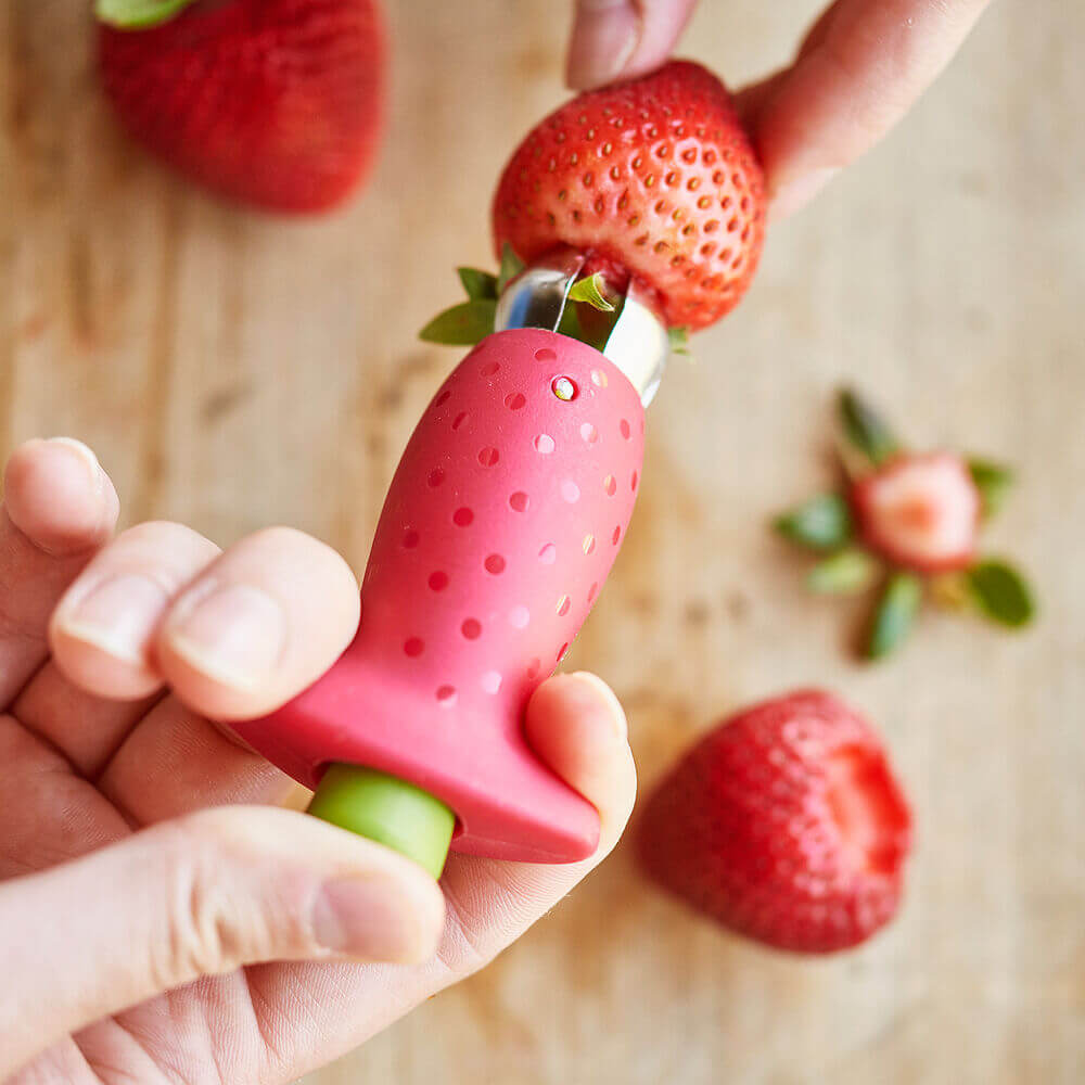 Samling av rena, taggade jordgubbar bredvid en smart jordgubbstagare, redo för bakning eller fika.