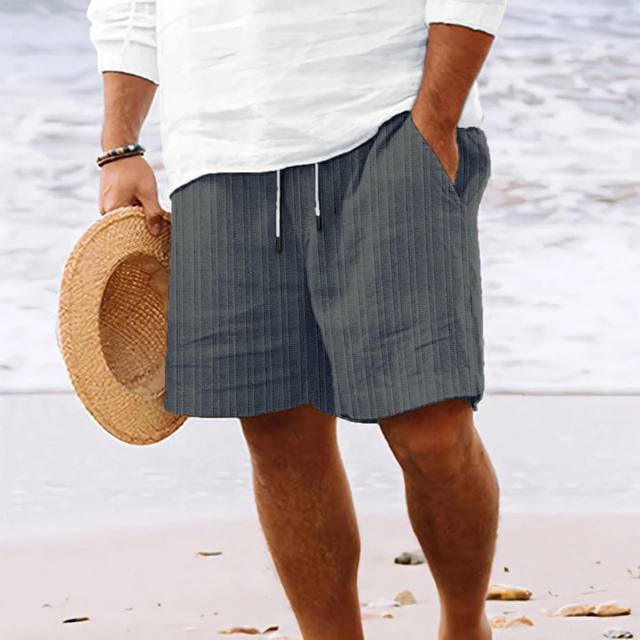 Modell bär snygga randiga herrshorts för en avslappnad sommarlook. Perfekta casual strandshorts.