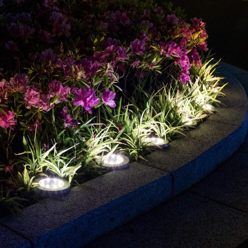 Varmvit LED markspotlight skapar mysig trädgårdsbelysning längs en gångväg på kvällen. Trådlös.