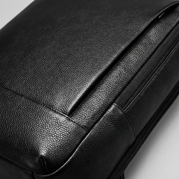 Elegant svart laptopryggsäck i premium fullnarvsskinn, tidlös design för både arbets- och skolpendling.