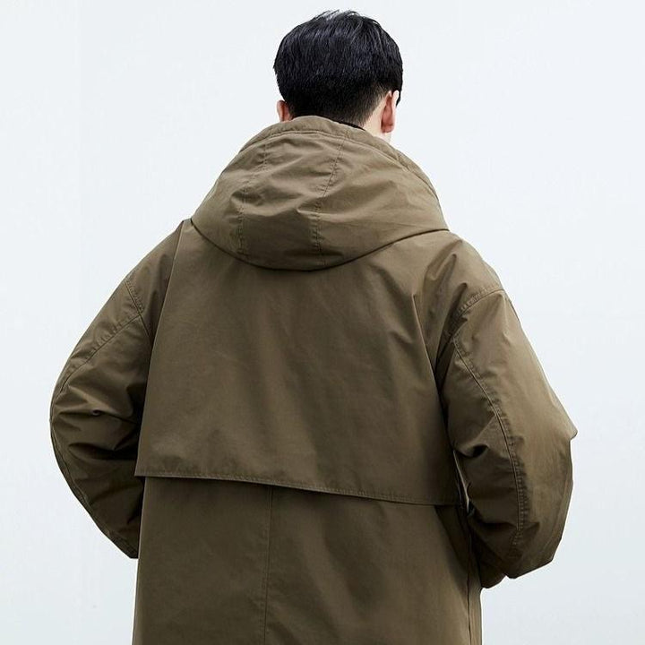 Man bär en avslappnad brun herr trenchcoat med huva. Modernt och bekvämt ytterplagg för alla väder.