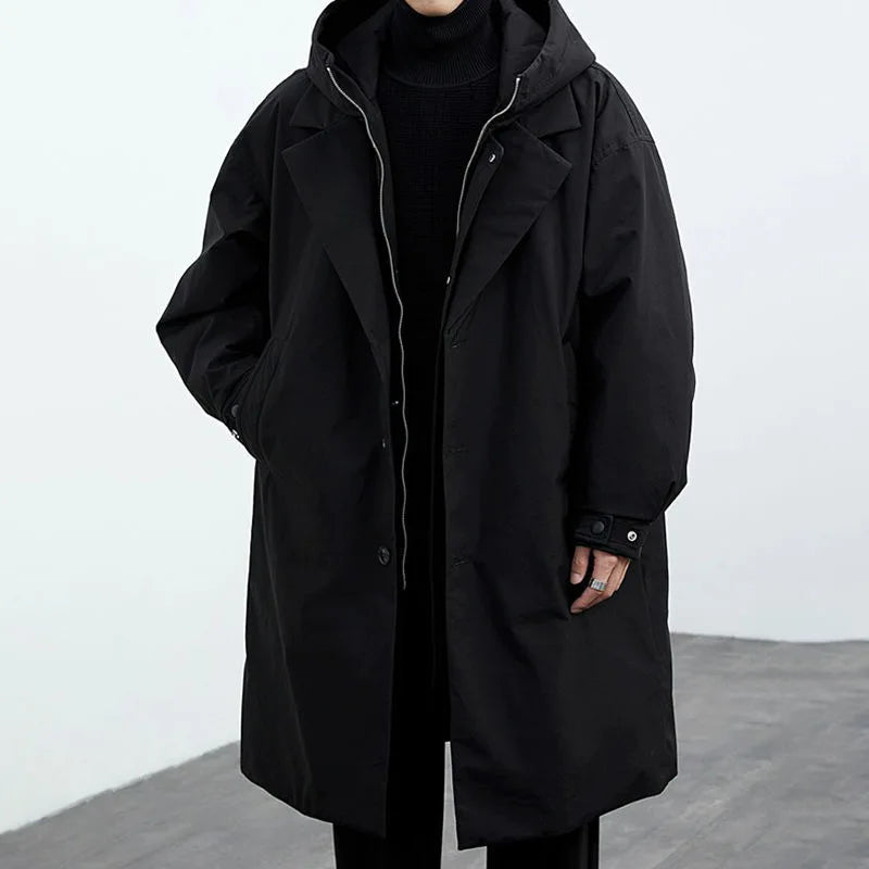 Helkroppsbild av en man som bär en modern svart trenchcoat med huva. Stilren och avslappnad herrjacka.