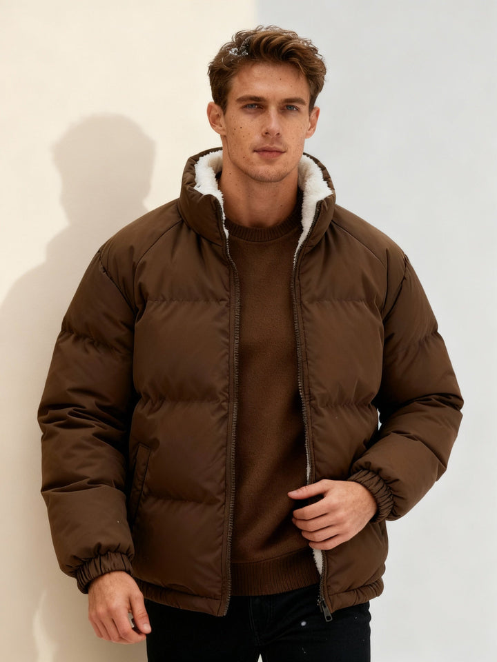Man bär en beige pufferjacka utomhus. En varm & stilren vinterjacka för sportig herrlook.