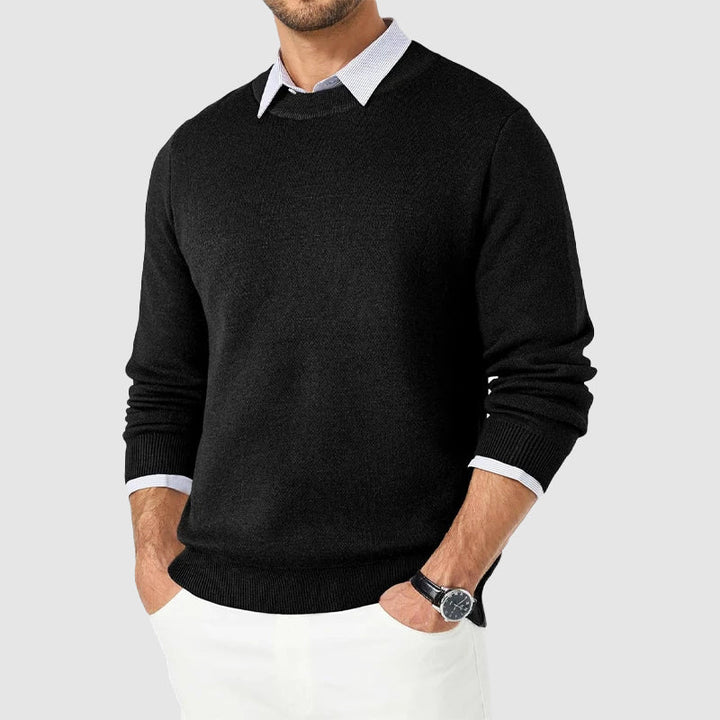 Man bär en snygg rundhalsad stickad herrtröja, kombinerar stilren design med komfort för höst/vår.