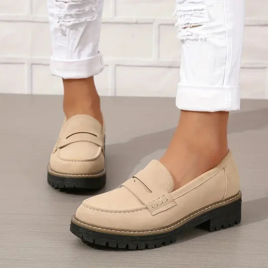 Närbild på fötter i bekväma plattform loafers. Stilrena damskor, perfekta för kontor.