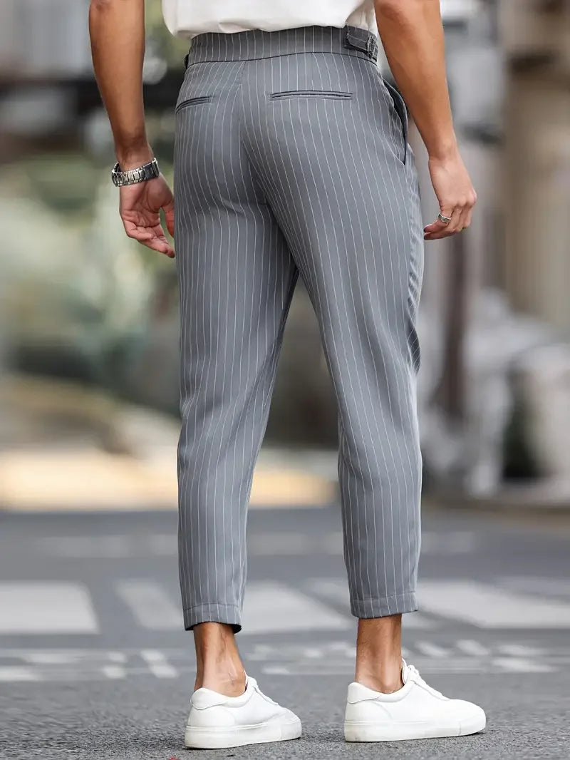 Man bär stilrena randiga herrbyxor, kombinerade med en tröja för en avslappnad men elegant look.