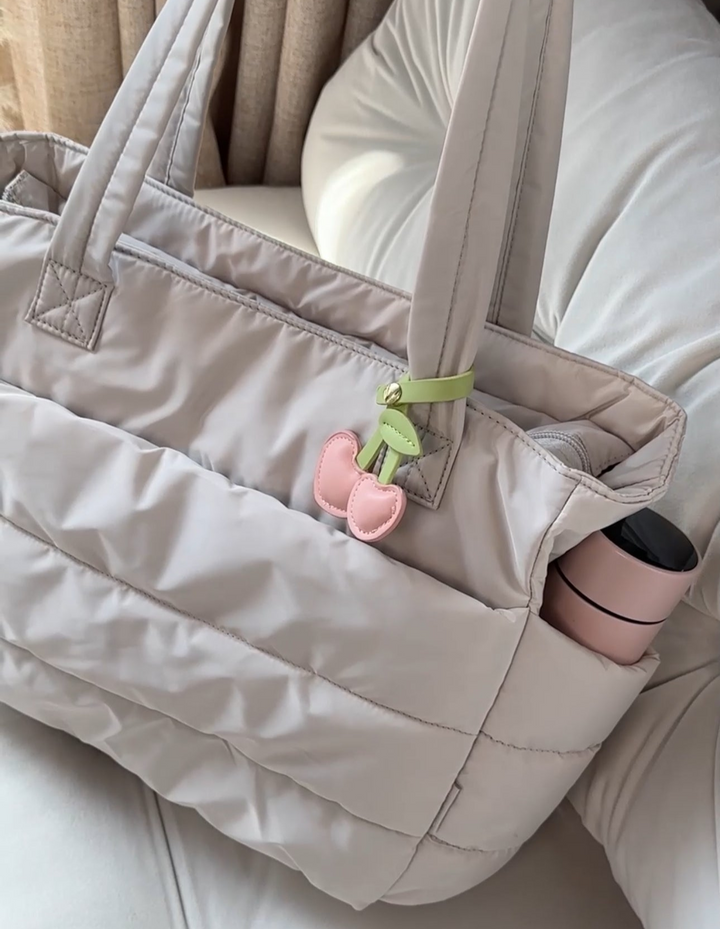 Närbild på textur av Dam Puffer Tote Bag. Exponerar det mjuka, vadderade materialet, vattentålig yta.