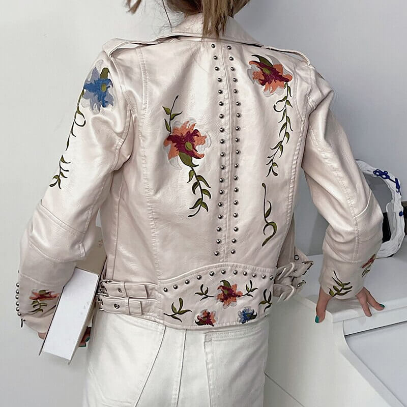 Beige asymmetrisk damjacka i konstläder med broderade blommor, en elegant ytterkläder.