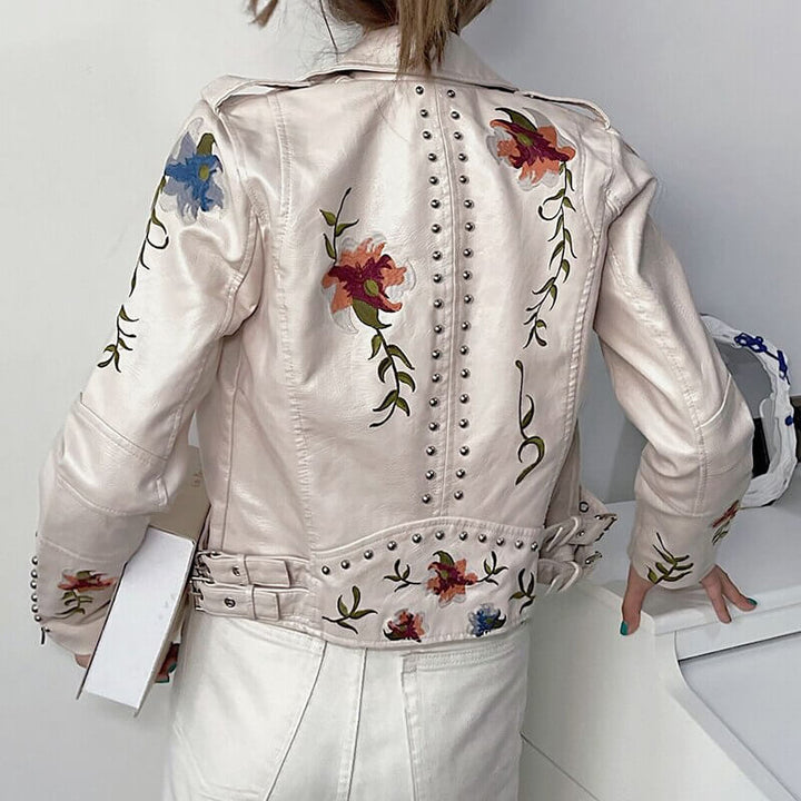 Beige asymmetrisk damjacka i konstläder med broderade blommor, en elegant ytterkläder.