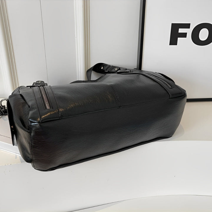 Svart axelremsväska för kvinnor, designad som en crossbody, med säker dragkedja och slitstarkt vegetabiliskt läder.
