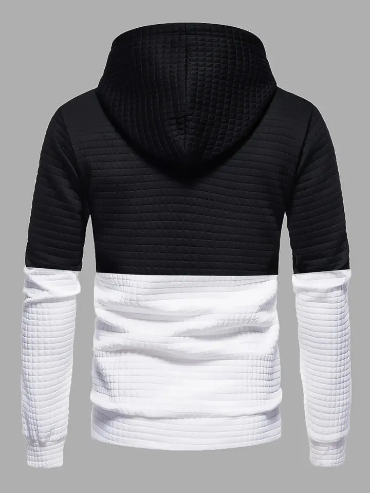 Man bär stilren svart herrhoodie med våffelmönster, perfekt för en avslappnad och modern look.