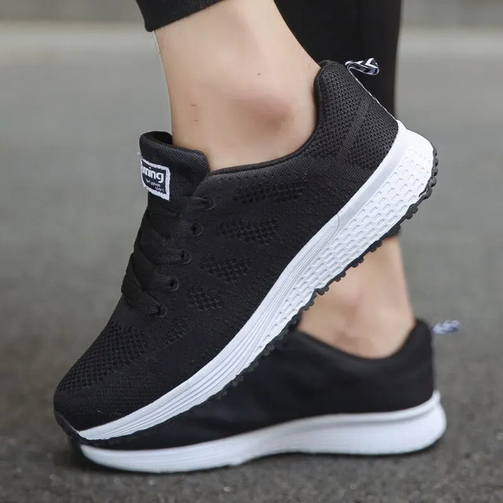 Närbild på svarta kvinnors lätta sneakers. Detaljer av andningsbart material och flexibel komfortsula.