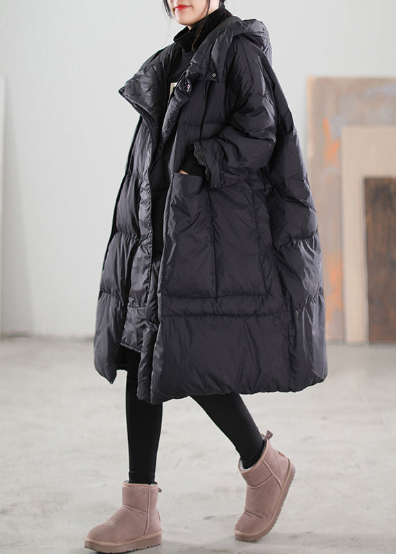 Plus size damvinterjacka i svart, lång modell med huva, fickor. Bekväm och varm dunjacka med lös passform.