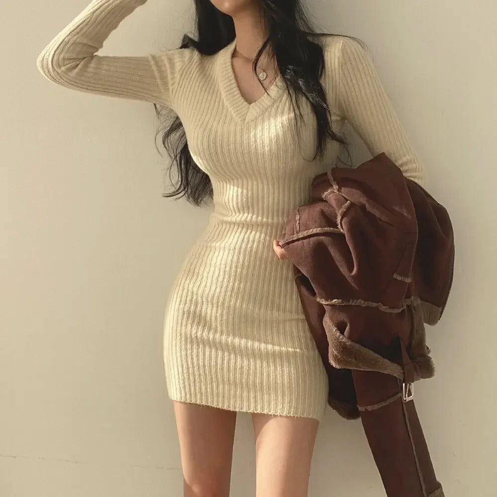 Grå V-ringad damklänning, stickad bodycon stil. Långärmad elegant klänning som framhäver formen.