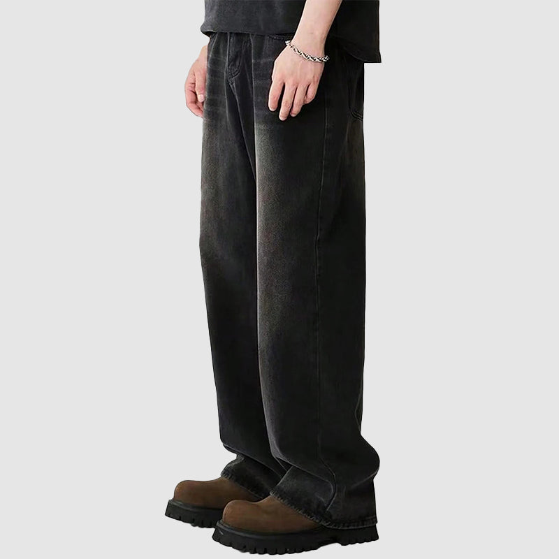 Man bär gråa baggyjeans med vida ben, en avslappnad & trendig stil för den moderna mannen.