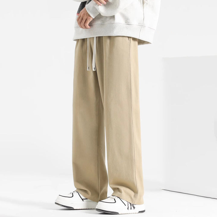 Man bär svarta mjukisbyxor herr, visar avslappnad passform och sportig stil. Perfekta för fritid.