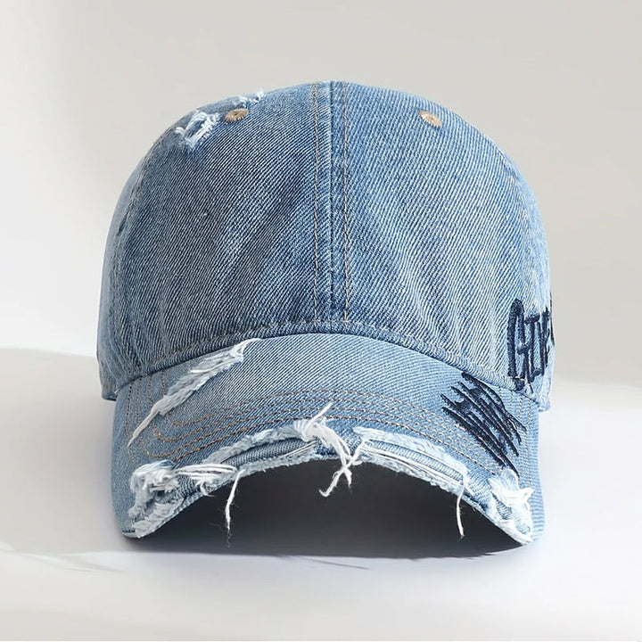 Närgångsbild på broderad denimkeps med slitna detaljer. En mångsidig unisex keps för streetwear-looken.